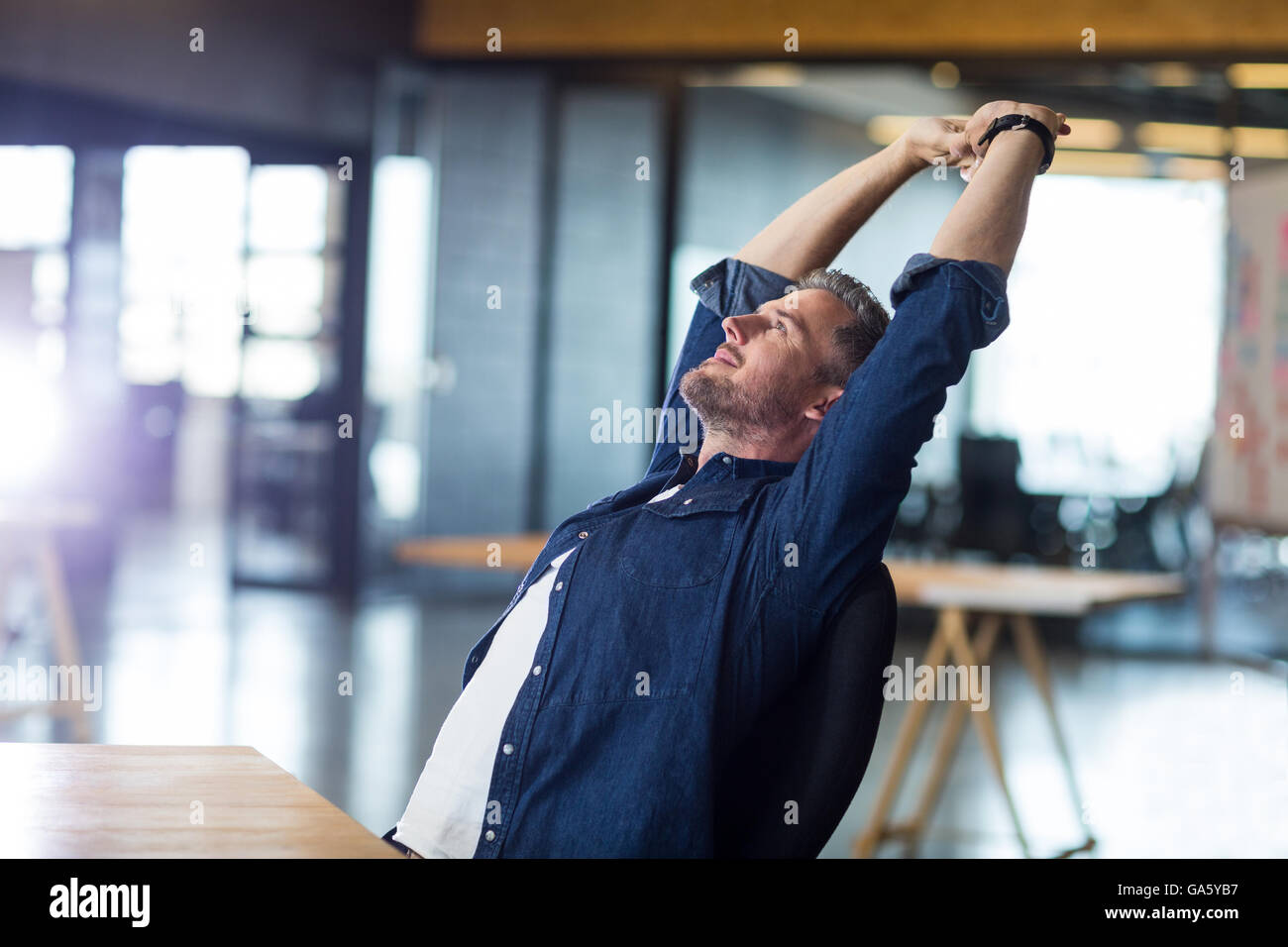 Relaxed man sitting in office Stock Photo