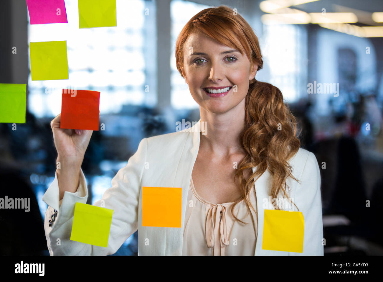 Portrait of businesswoman writing on adhesive notes Stock Photo - Alamy
