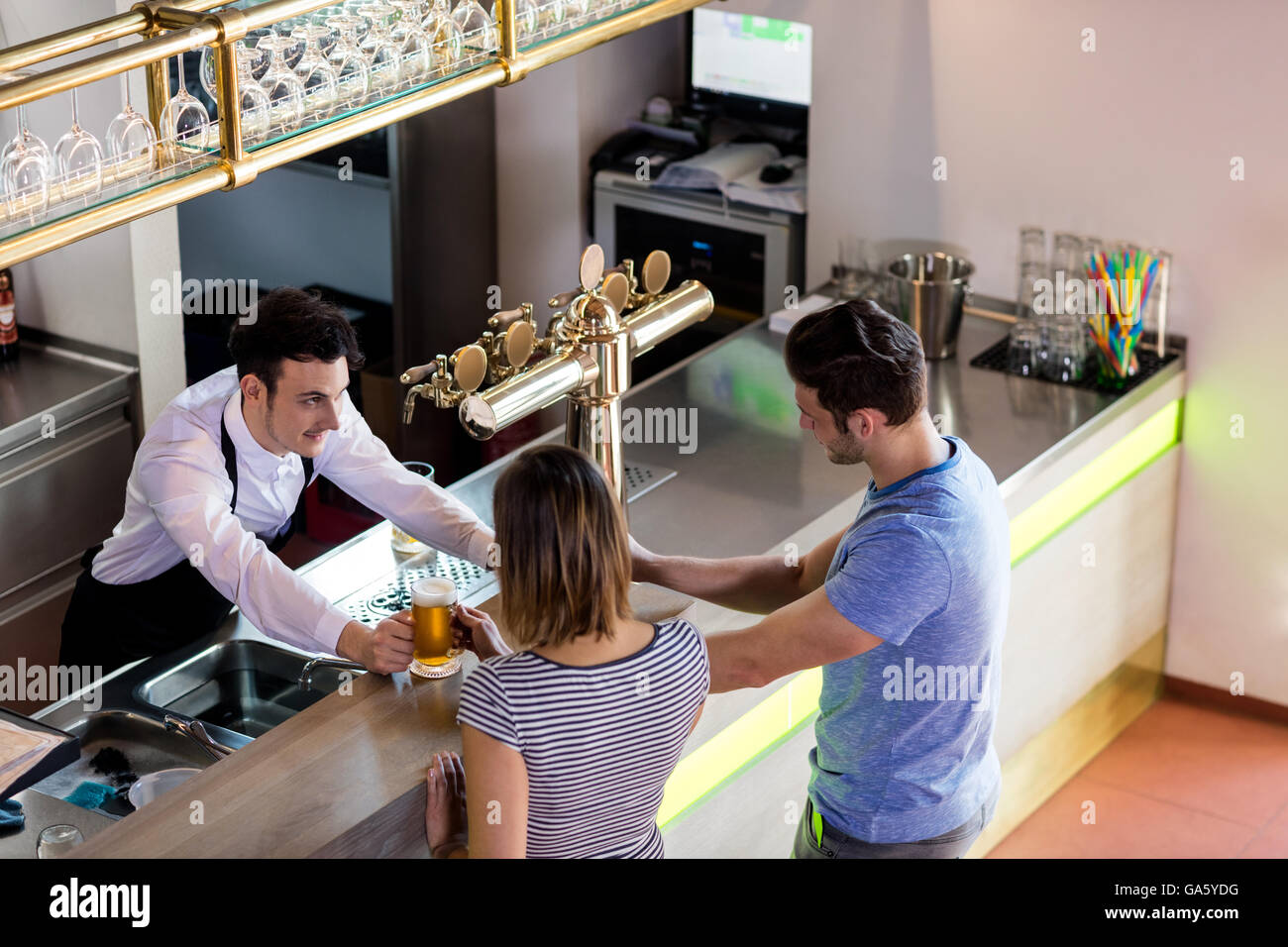Barkeeper serving beer to couple Stock Photo