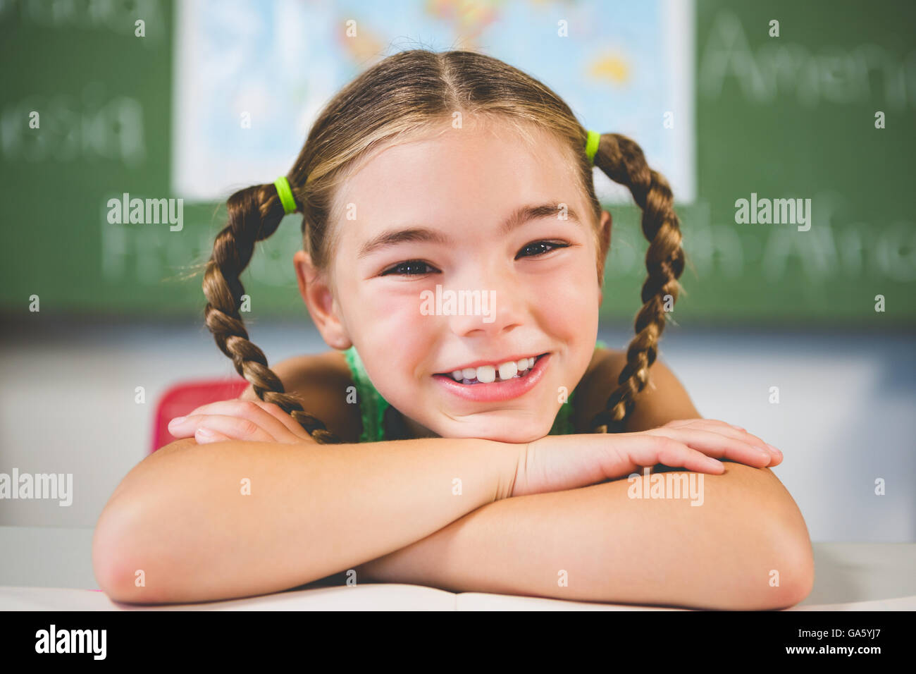 Portrait of schoolgirl leaning on a book in classroom Stock Photo - Alamy