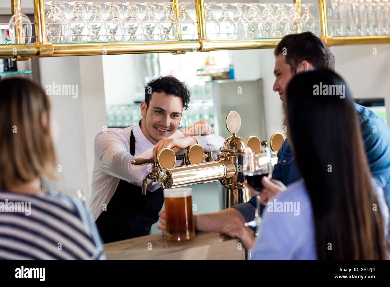 Friends talking to barkeeper while having drinks Stock Photo