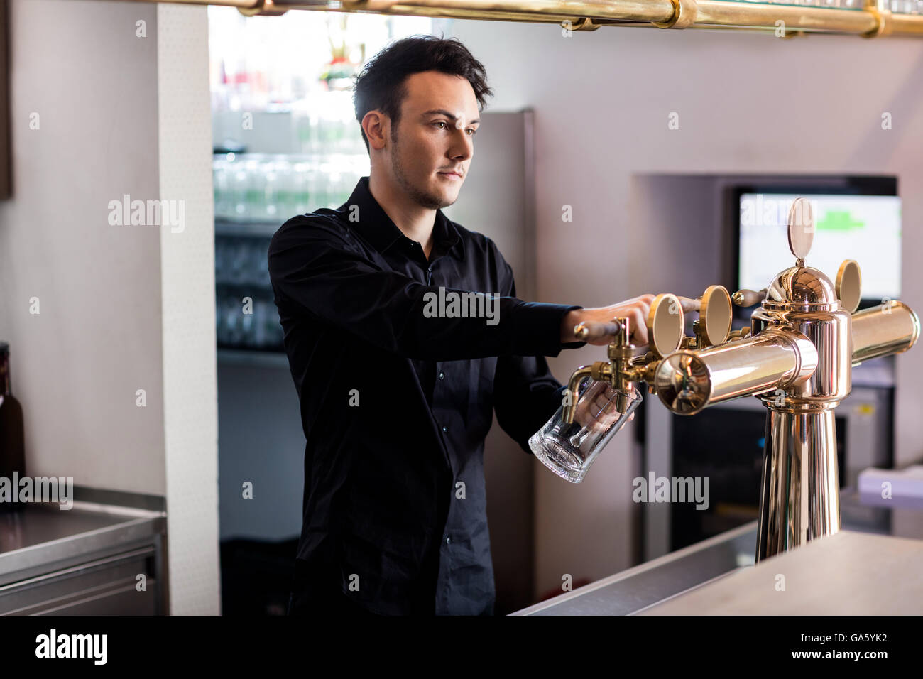 Barkeeper pouring beer in glass from faucet Stock Photo