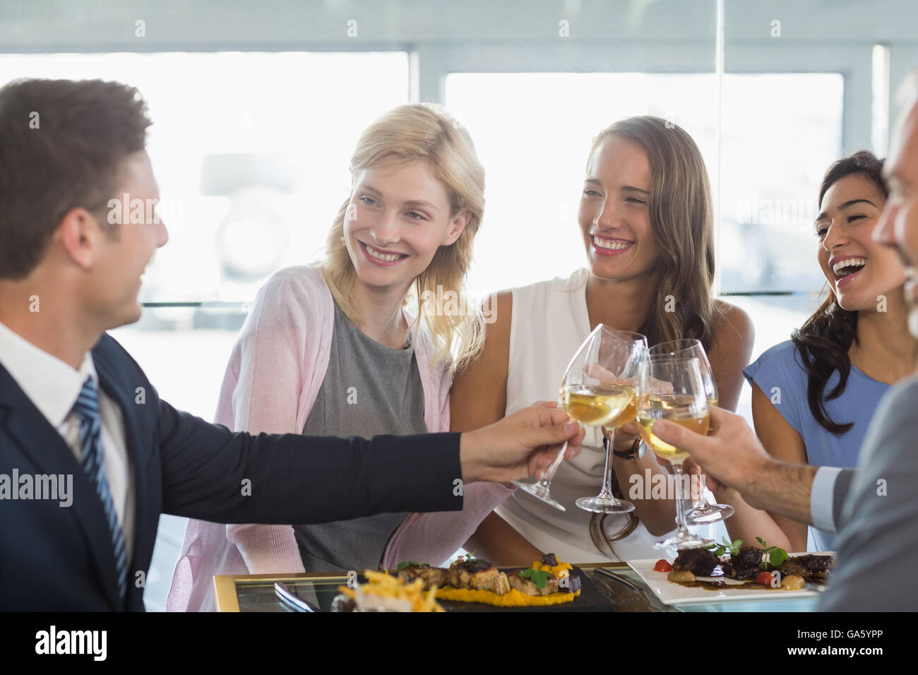 Happy business colleagues toasting beer glasses while having lunch Stock Photo
