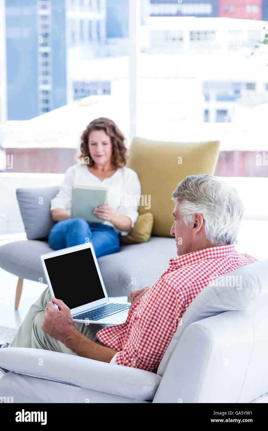 Mature man using notebook while sitting by woman Stock Photo