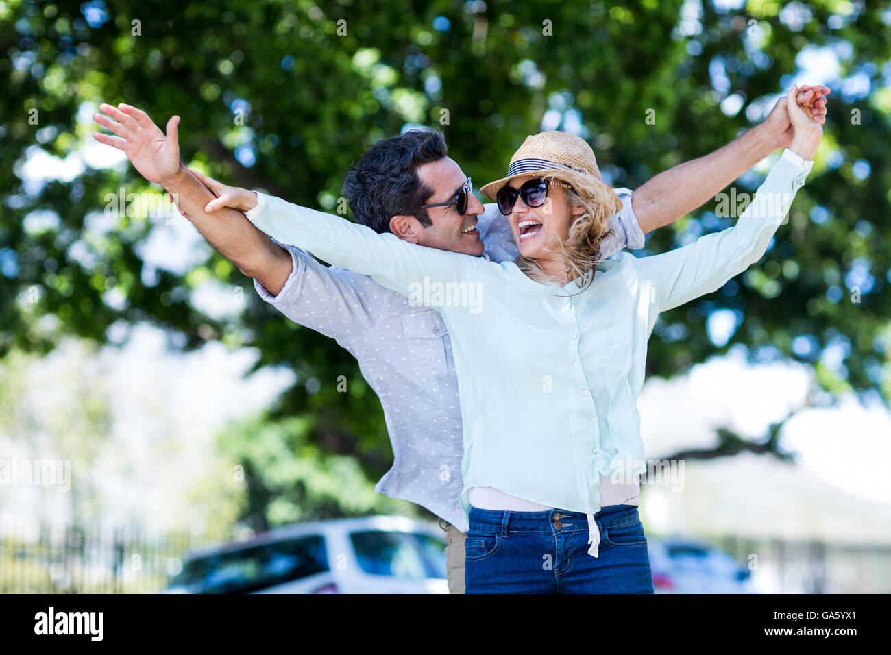 Couple with arms outstretched against trees Stock Photo