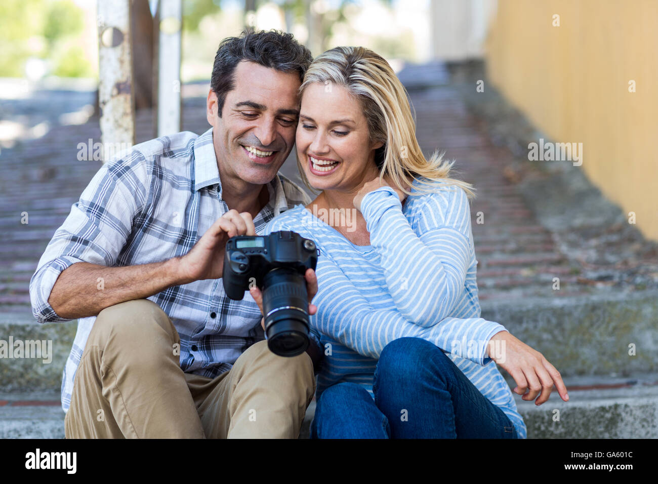 Couple looking in camera while sitting on steps Stock Photo