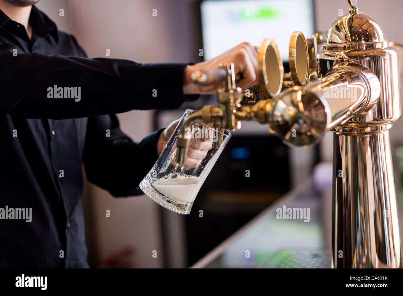 Bartender pouring beer from faucet in pint glass Stock Photo