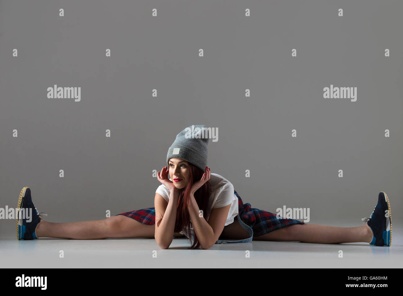 One fit young woman wearing casual funny hat bending forward sitting in splits. Modern style beautiful teen cool dancer working Stock Photo