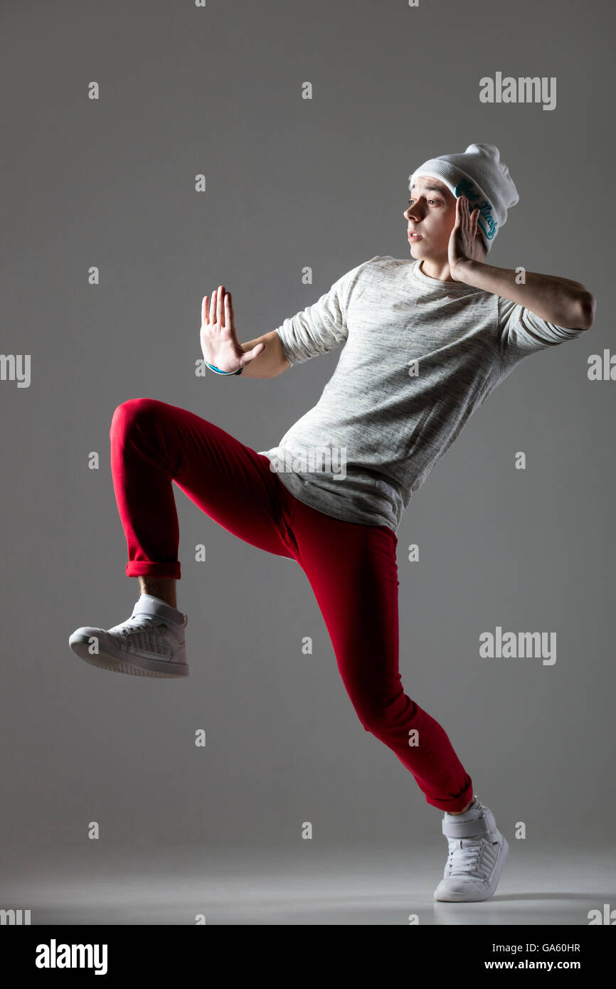 Portrait of one funny hipster young man dancing wearing casual red jeans and beanie. Cool hip-hop dancer guy working out Stock Photo