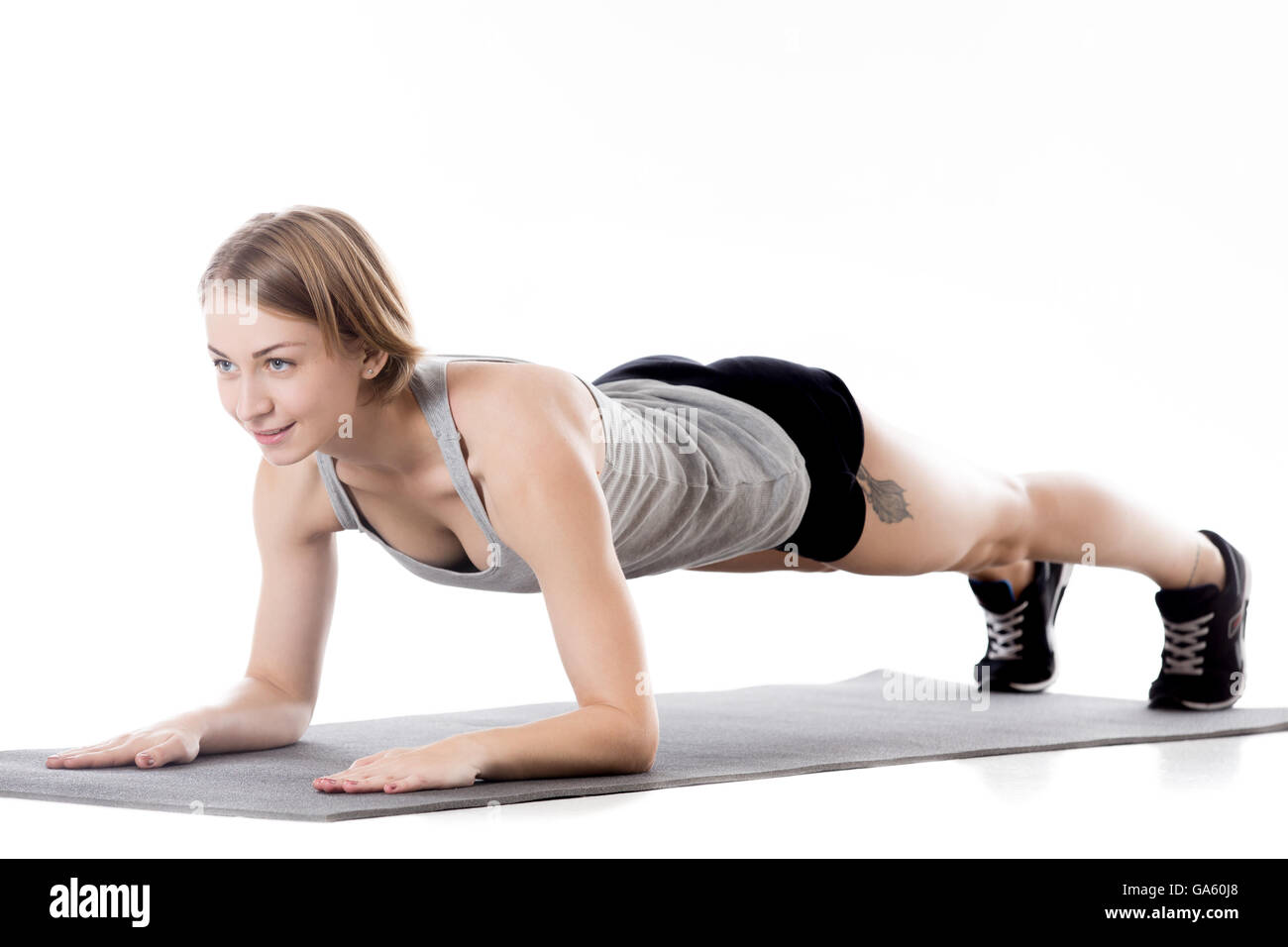 Portrait of young cheerful slim sporty beautiful woman working out on mat, warming up, doing plank exercises, isolated studio Stock Photo