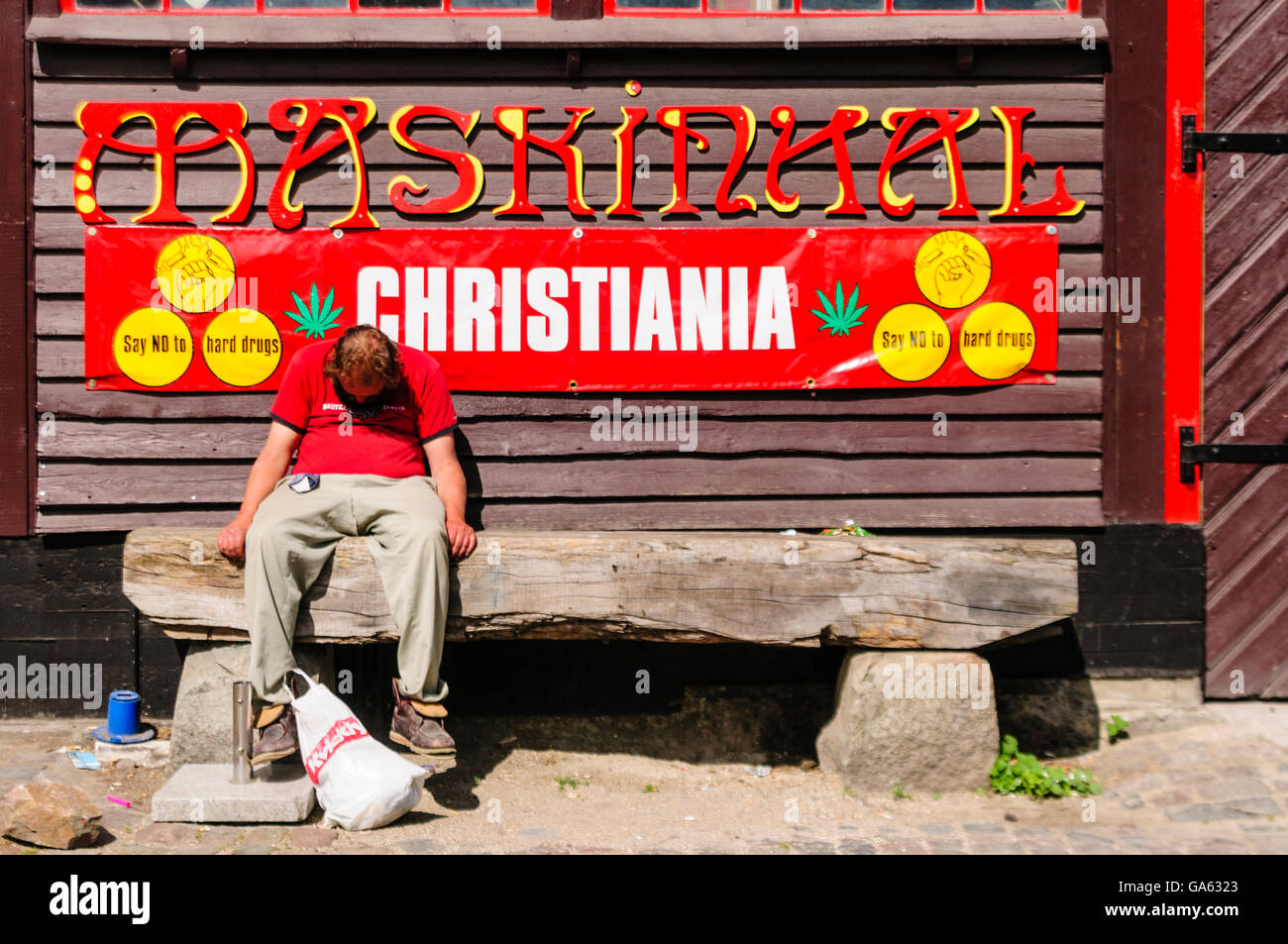 A man sits sleeping in front of a sign saying 'Say NO to hard drugs' in Freetown Christiana, Copenhagen Stock Photo