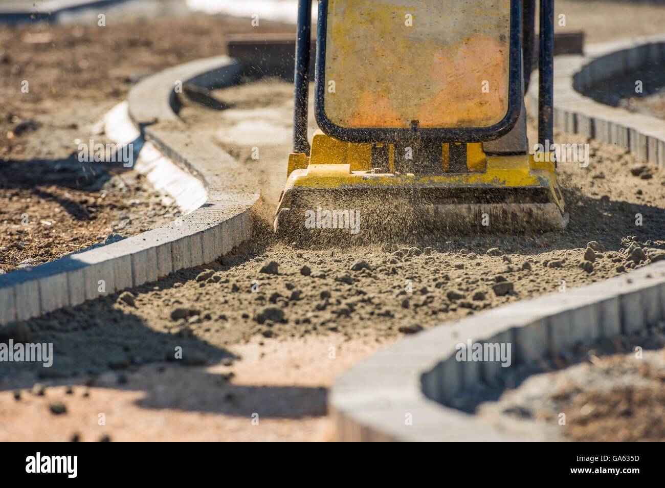 Plate Compactor in Action. Compacting Soil For a Brick Pavement Stock