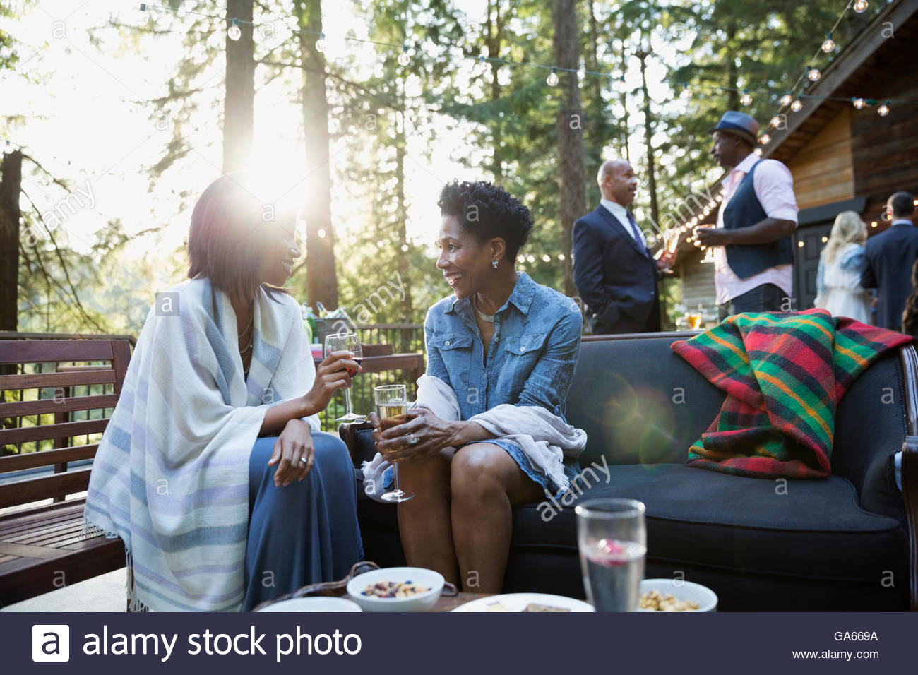 Women drinking wine and talking at party on cabin balcony in sunny