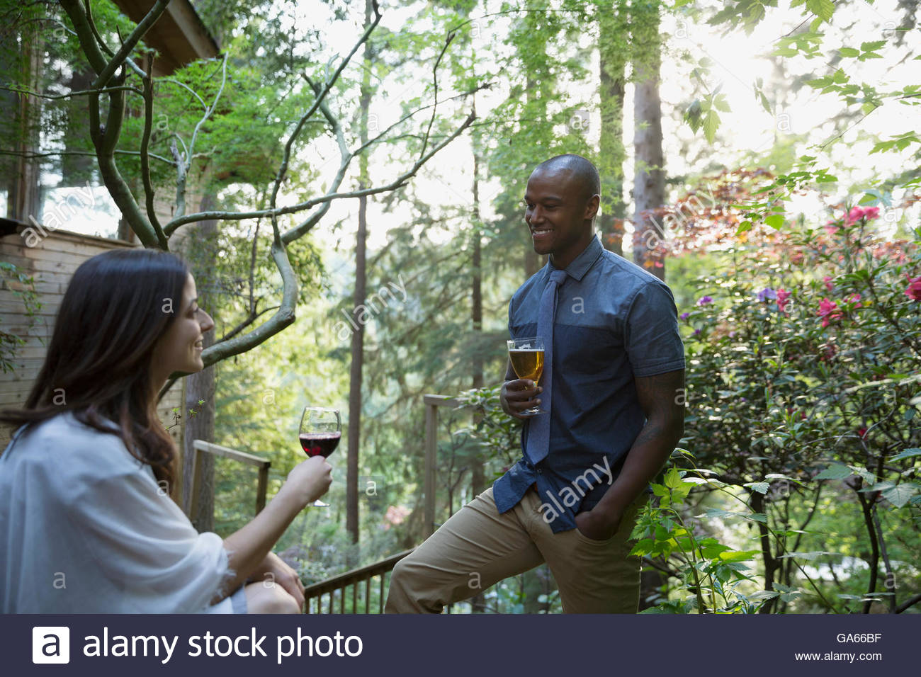 Couple drinking beer and wine outside cabin in woods Stock Photo Alamy