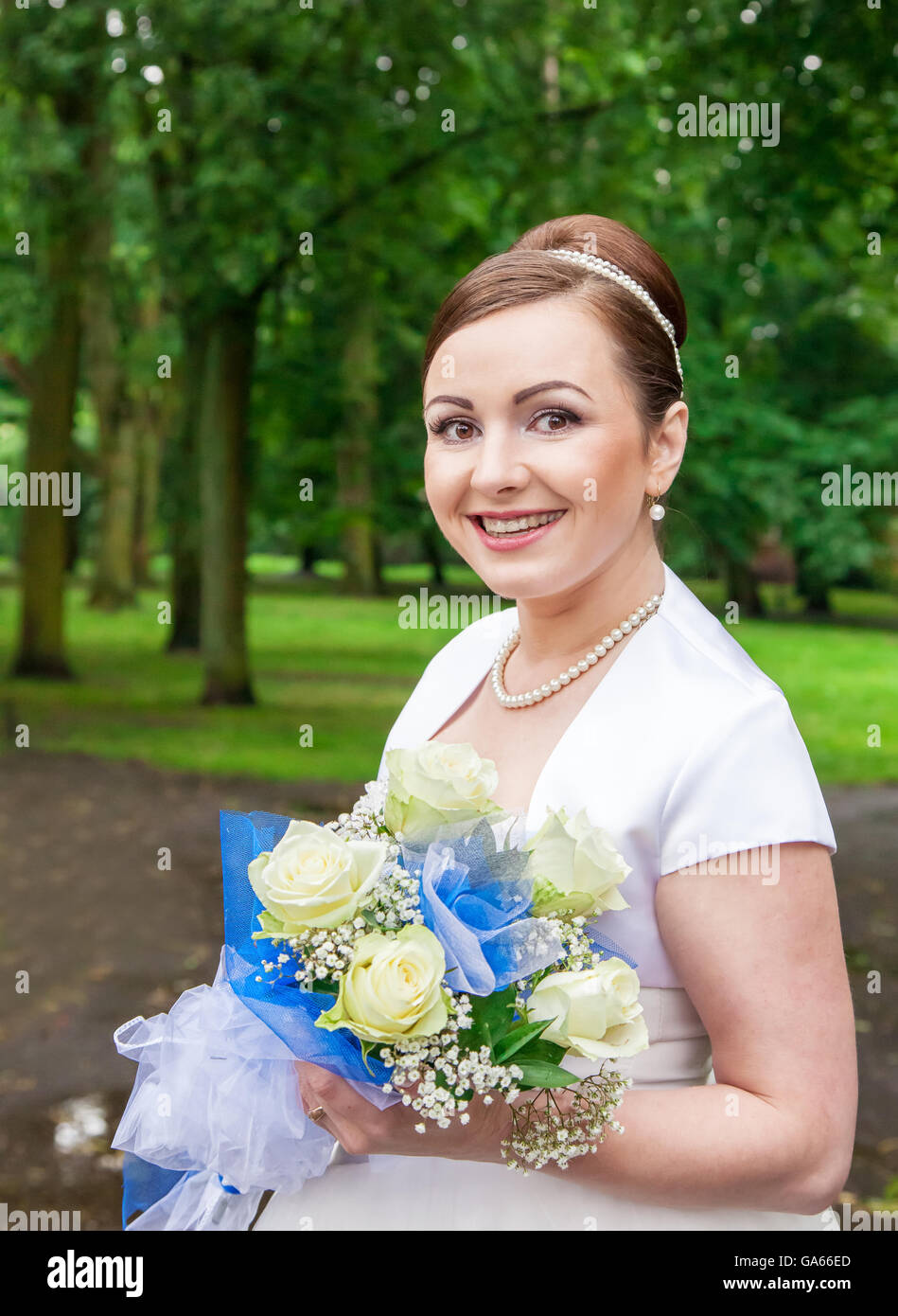 portrait of young smiling bride with a bouquet of white roses outside ...