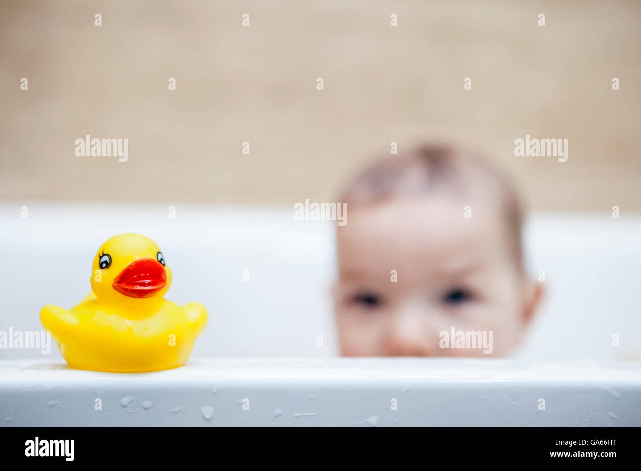 9 months baby boy having fun in the bathtub. Rubber duck on the border Stock Photo