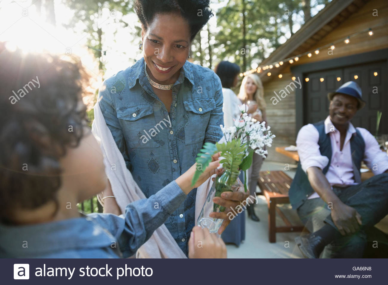 Grandson giving grandmother fresh picked flowers at balcony party Stock Photo