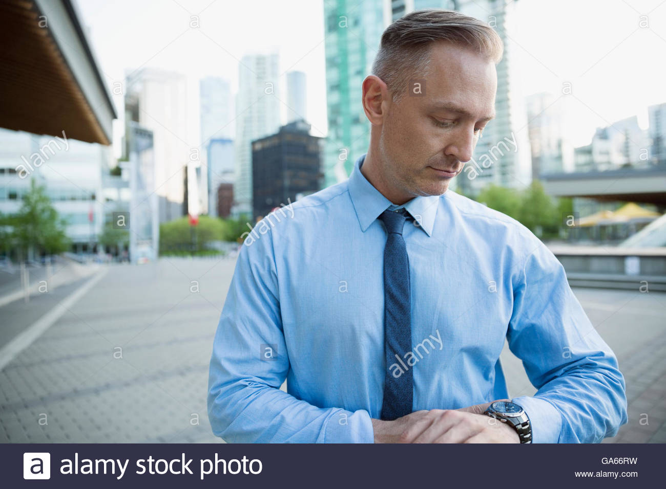 Portrait businessman checking the time on wristwatch in city Stock ...