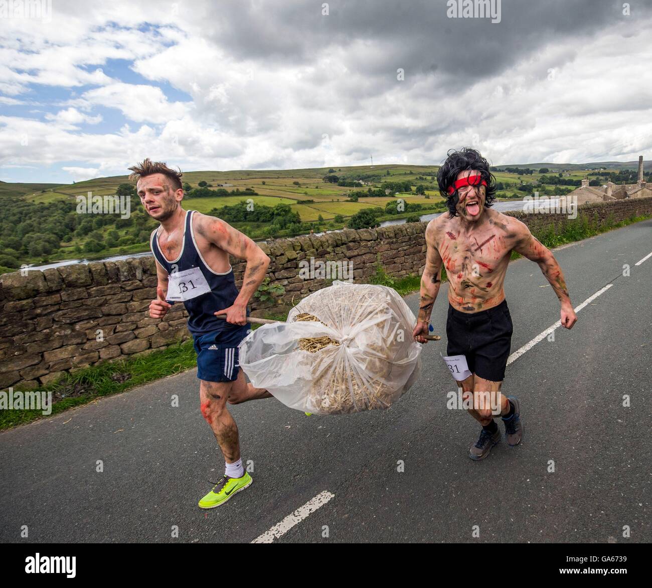 Competitors takes part on the Oxenhope Straw Race in Yorkshire, which involves running in fancy dress, whilst carrying a bale of straw and visiting each of the local pubs in the village to raise money for local charities. Stock Photo