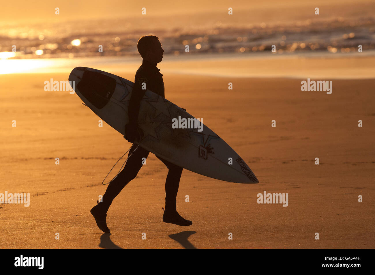 surfer running on beach in silhouette at sunset Stock Photo - Alamy