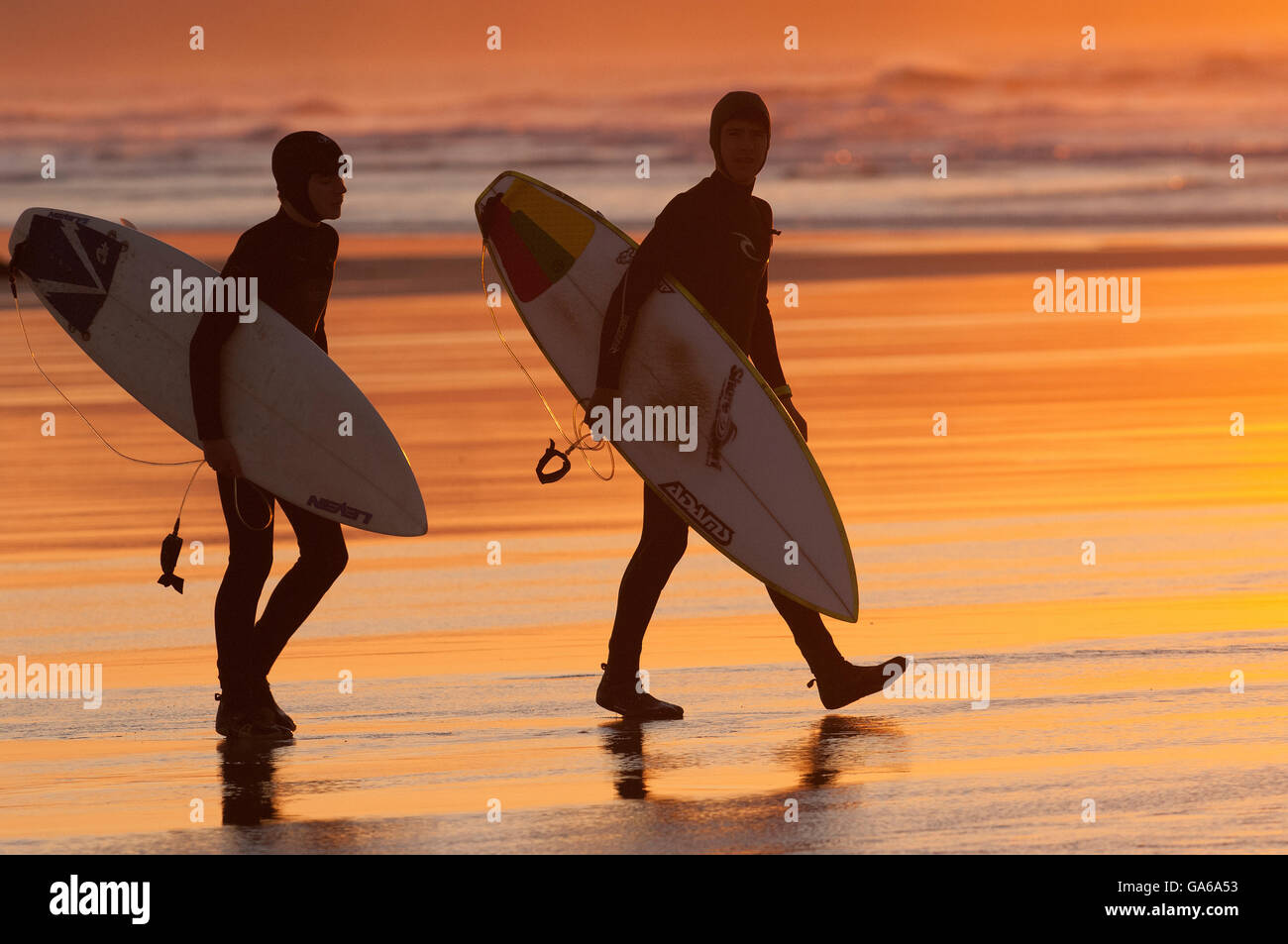 surfers on beach in silhouette at sunset Stock Photo - Alamy