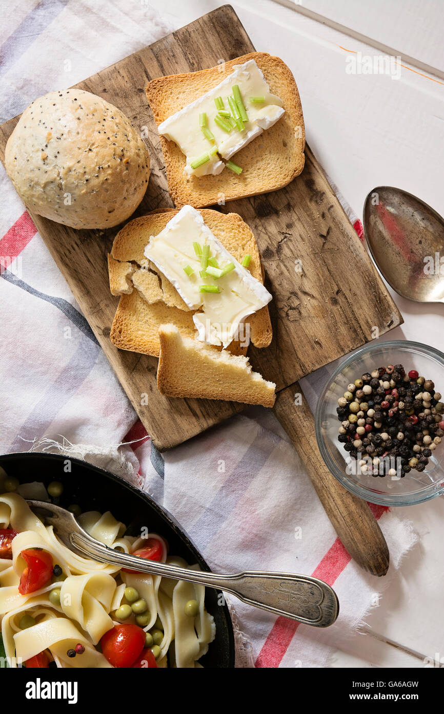 toasted bread, with brie cheese and chives on wooden board Stock Photo