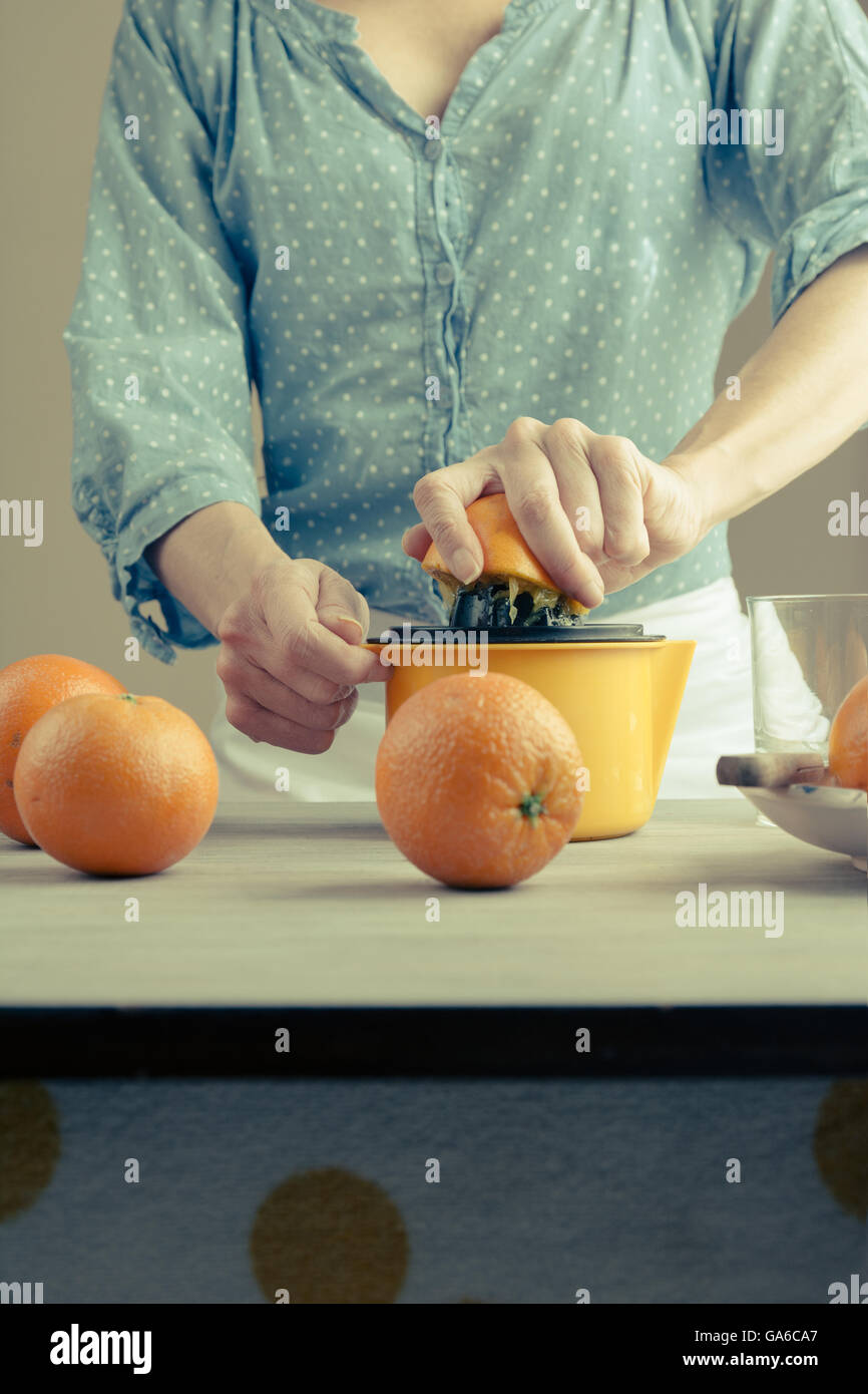 Woman squeezing oranges on a table, preparing juice, flat closed Stock Photo