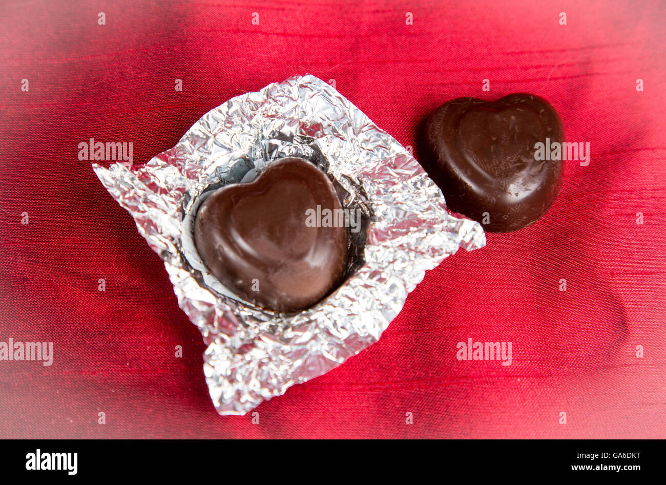 Heart shaped valentine's day chocolate candies on a red background. Stock Photo