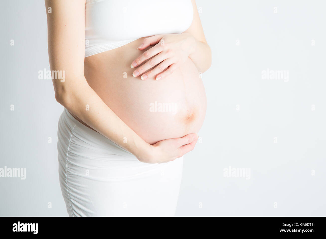 A woman craddles her pregnant belly. 9 months pregnant. Stock Photo