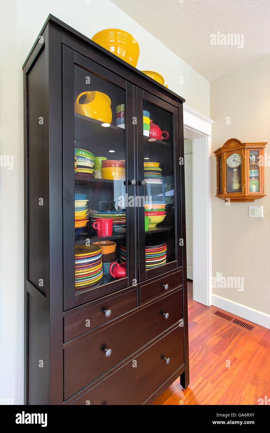 Wood China Cupboard with colorful dinnerware and Oak Pendulum Clock interior home Stock Photo