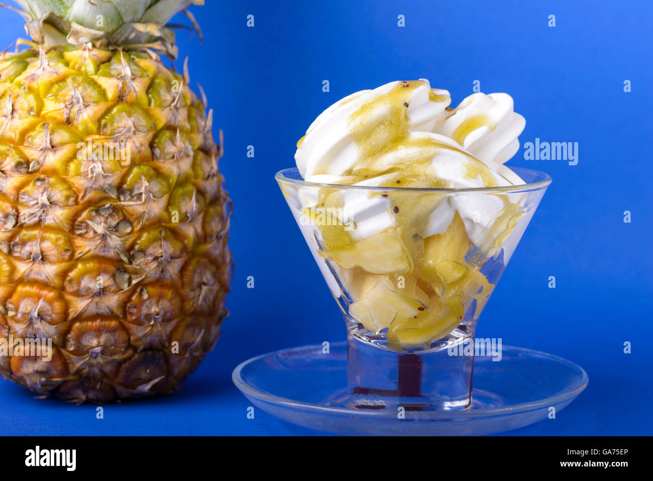 frozen yogurt with kiwi topping and pineapple in glass bowl on blue background with pineapple Stock Photo