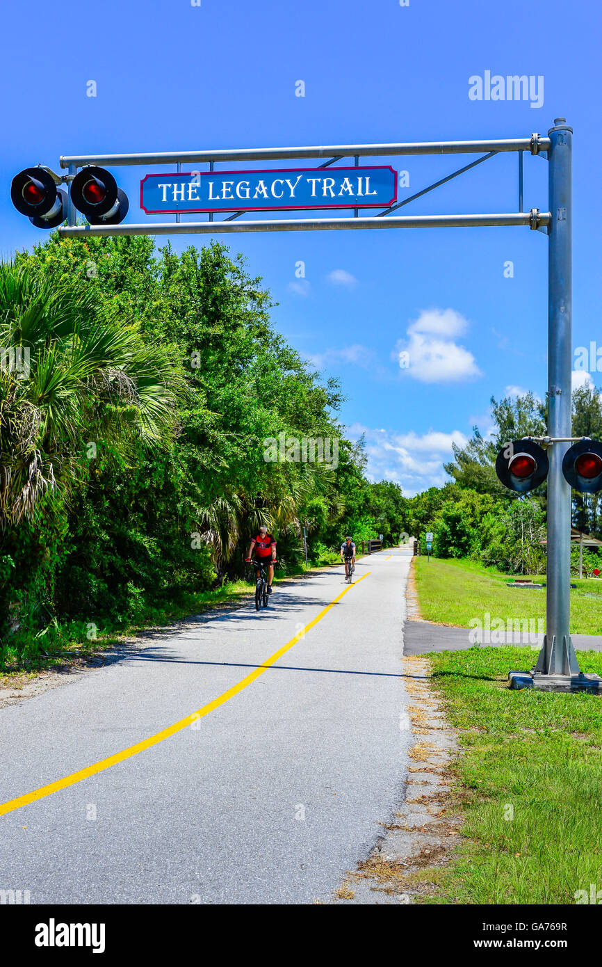 Bicyclists enjoy a sunny day on the Legacy Trail bike path near the Train Depot in downtown Venice, FL Stock Photo
