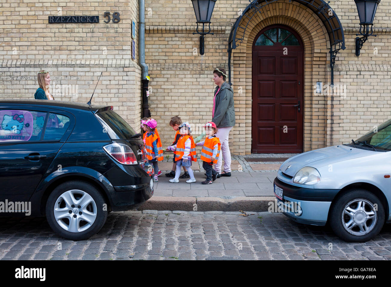 School children in orange hi viz vests walk along the pavement with teachers in an orgnised group for safety in Gdansk, Poland Stock Photo