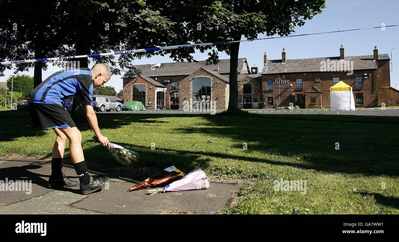 A boy lays flowers at the scene outside outside the Fir Tree pub in