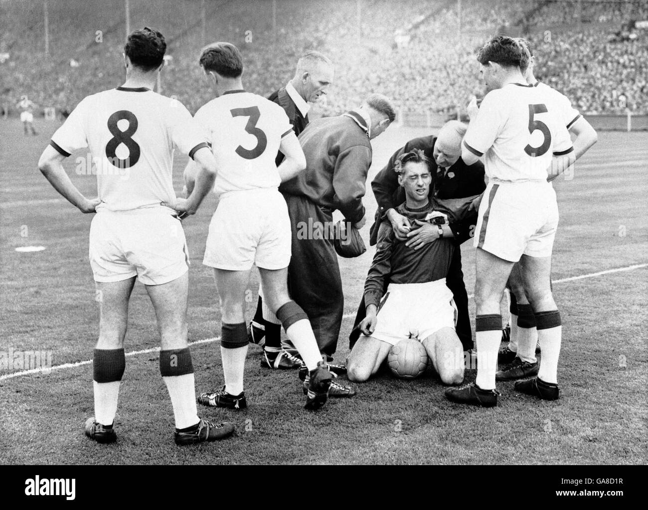 Manchester United goalkeeper Ray Wood (kneeling) receives treatment after having his cheekbone fractured in a clash with Aston Villa's Peter McParland Stock Photo
