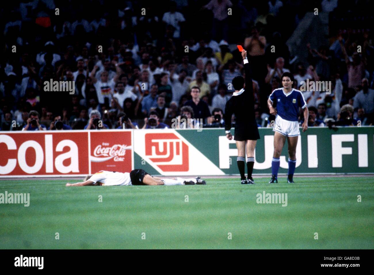 Referee Edgardo Codesal (c) sends off Argentina's Pedro Monzon (r) for a foul on the writhing Jurgen Klinsmann of West Germany (l) Stock Photo