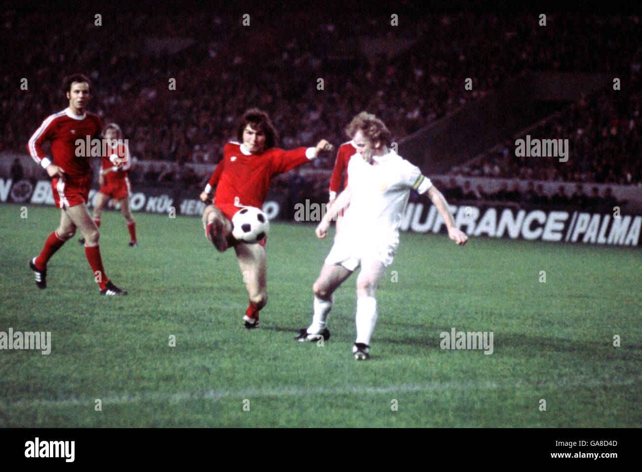 (L-R) Bayern Munich's Franz Beckenbauer looks on as a teammate hooks the ball away from Leeds United's Billy Bremner Stock Photo