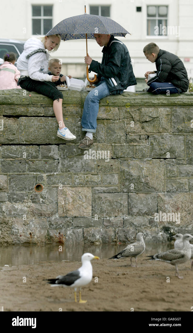 Holiday makers enjoy their fish and chips under the cover of an