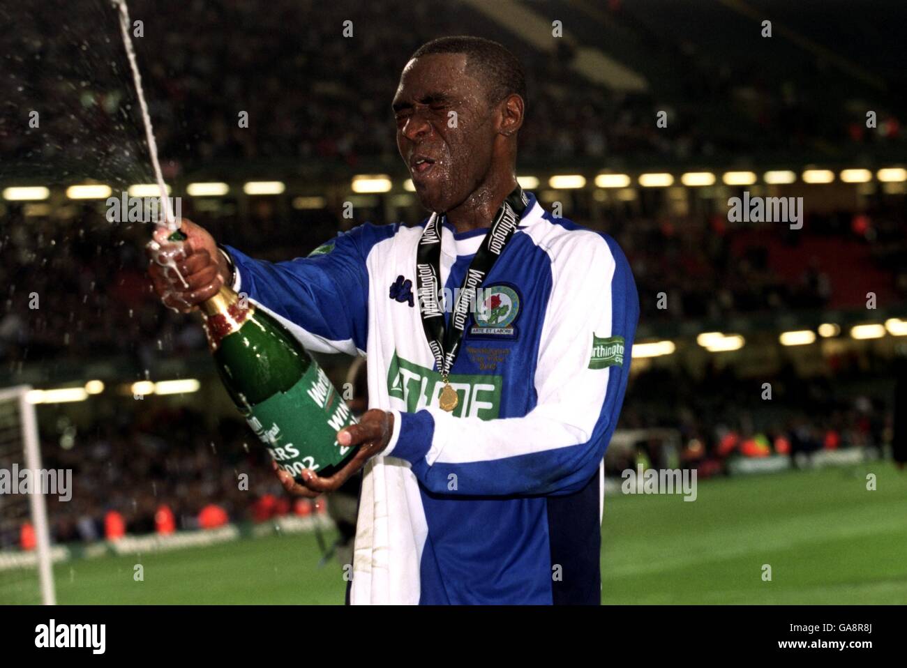 Blackburn Rovers' goalscorer Andy Cole celebrates by spraying champagne at the crowd Stock Photo