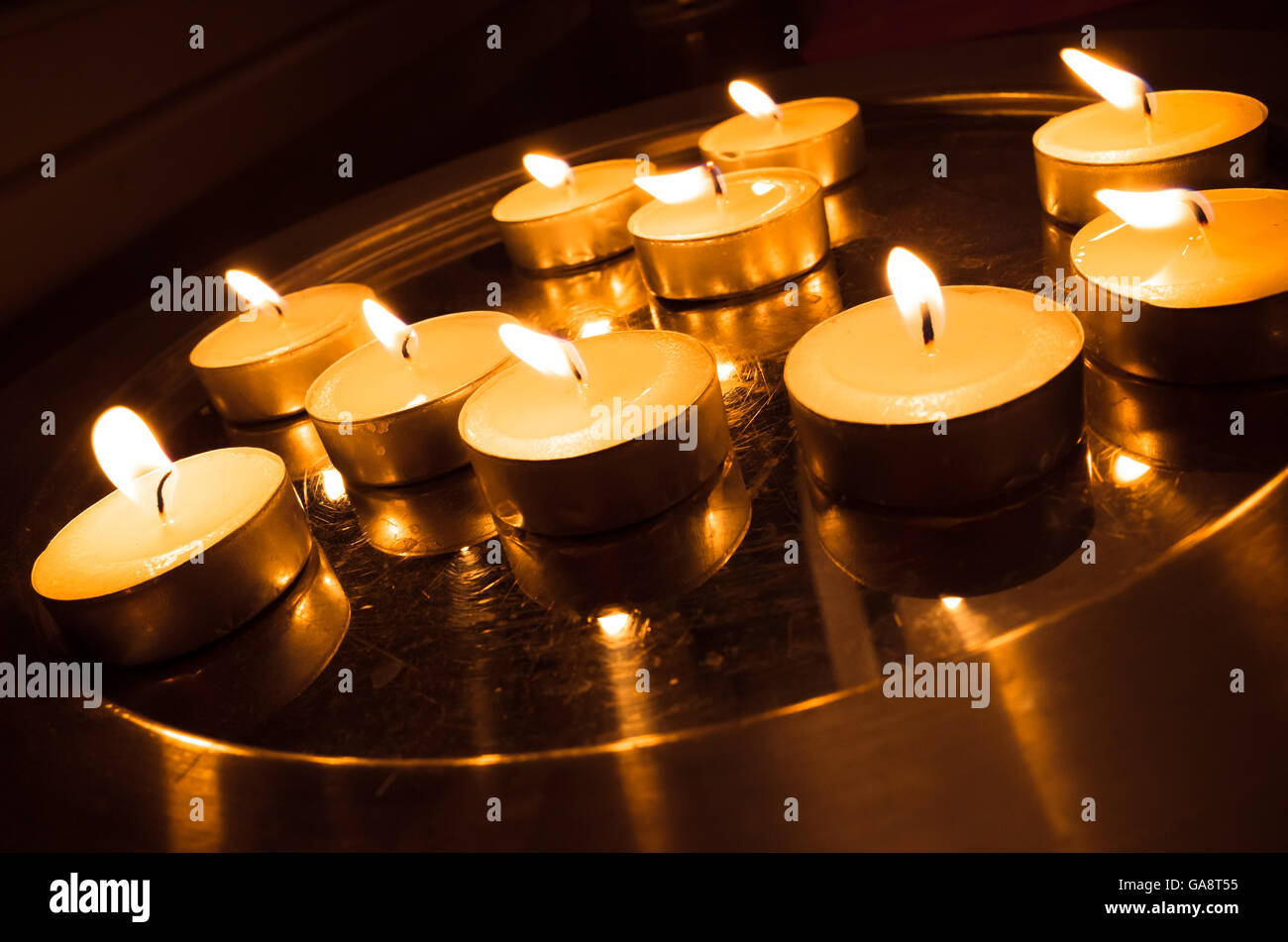 Group of pray candles burn on a metal stand in the church Stock Photo