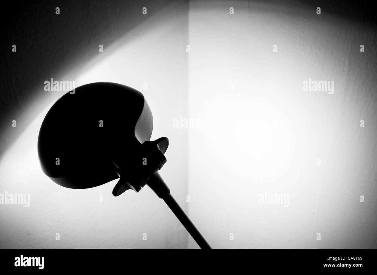 Reading lamp illuminates the corner of the room painted in white. Spot light and shadows Stock Photo