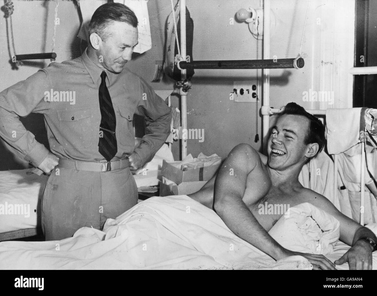 U.S. Secretary of the Navy James V. Forrestal's remarks amuse a wounded U.S. Marine in a hospital after the Battle of Iwo Jima. Stock Photo
