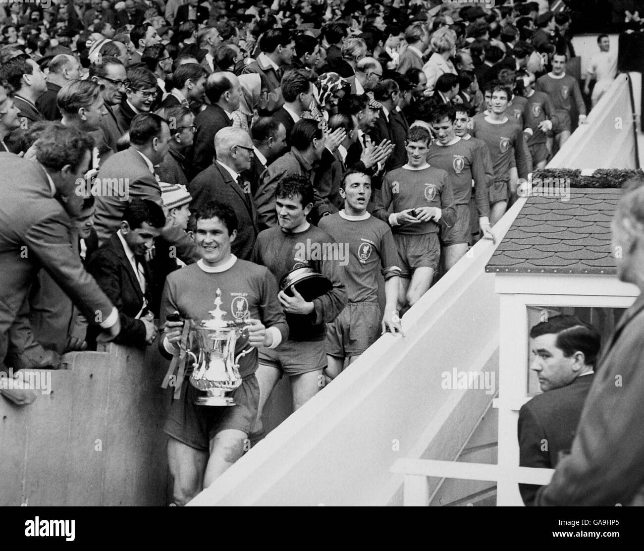 Liverpool captain Ron Yeats (l) carries the FA Cup down Wembley's 39 steps, followed by teammates Tommy Lawrence (carrying base of cup), Peter Thompson, Geoff Strong, Tommy Smith, Ian Callaghan, Wilf Stevenson, Chris Lawler, Roger Hunt, Ian St John and Gerry Byrne Stock Photo