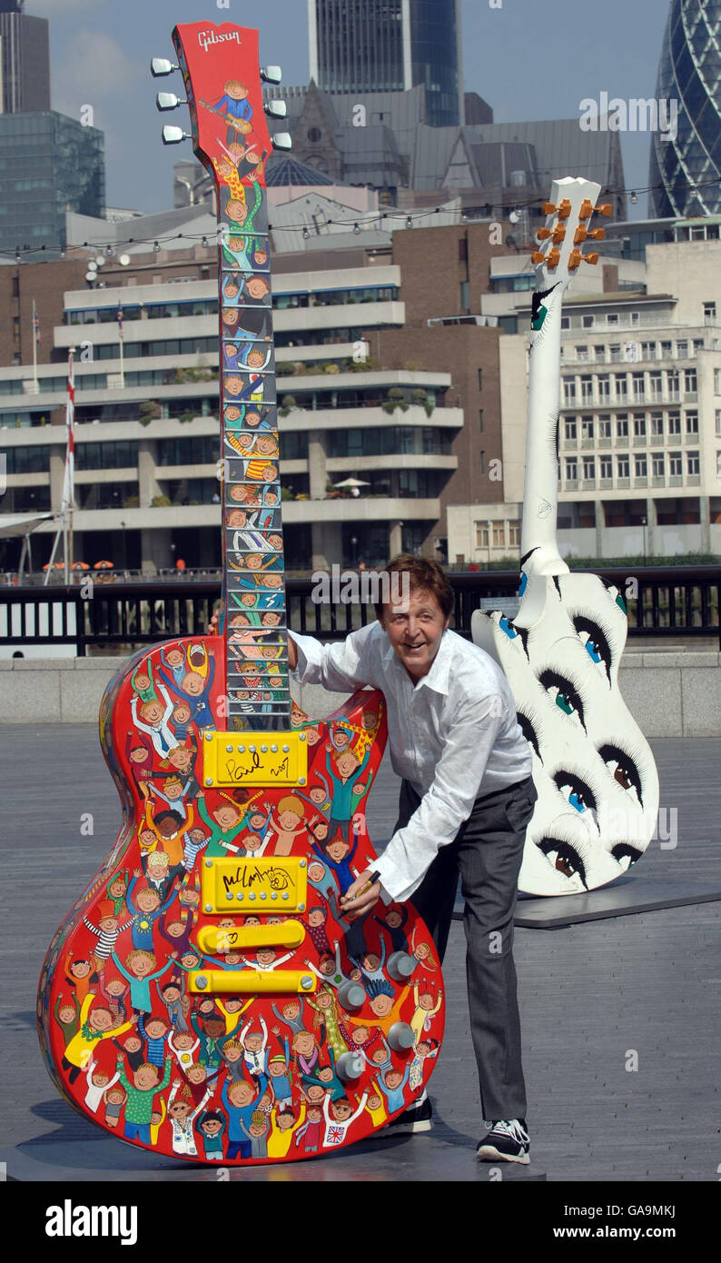 Sir Paul McCartney signs a 10ft high Les Paul Guitar sculpture in central London, painted by artist Rosie Brooks, which forms part of an exhibition at London's City Hall. The guitar along with many others will be auctioned in November to raise money for the Prince's trust. Stock Photo