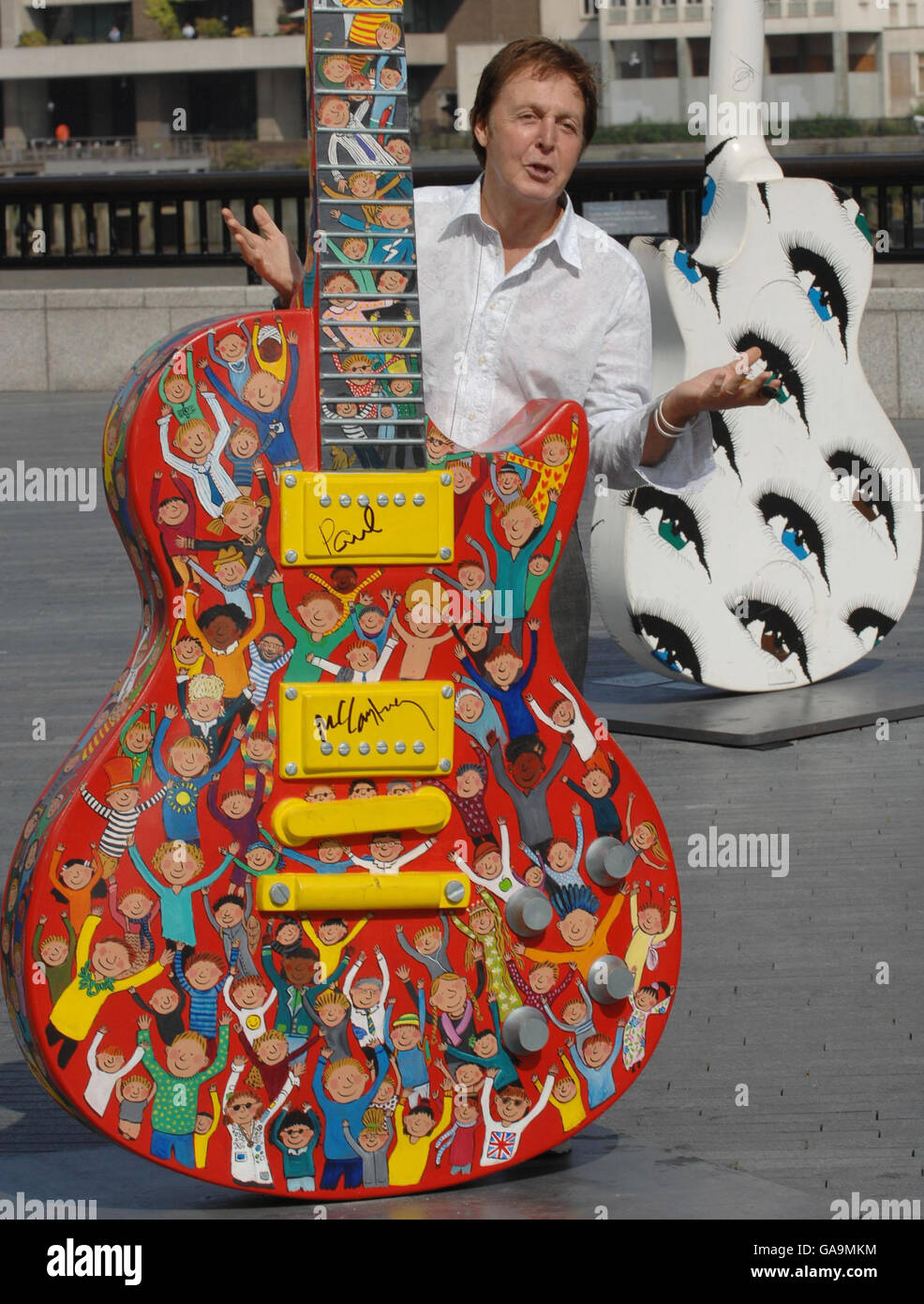 Sir Paul McCartney signs a 10ft high Les Paul Guitar sculpture in central London, painted by artist Rosie Brooks, which forms part of an exhibition at London's City Hall. The guitar along with many others will be auctioned in November to raise money for the Prince's trust. Stock Photo
