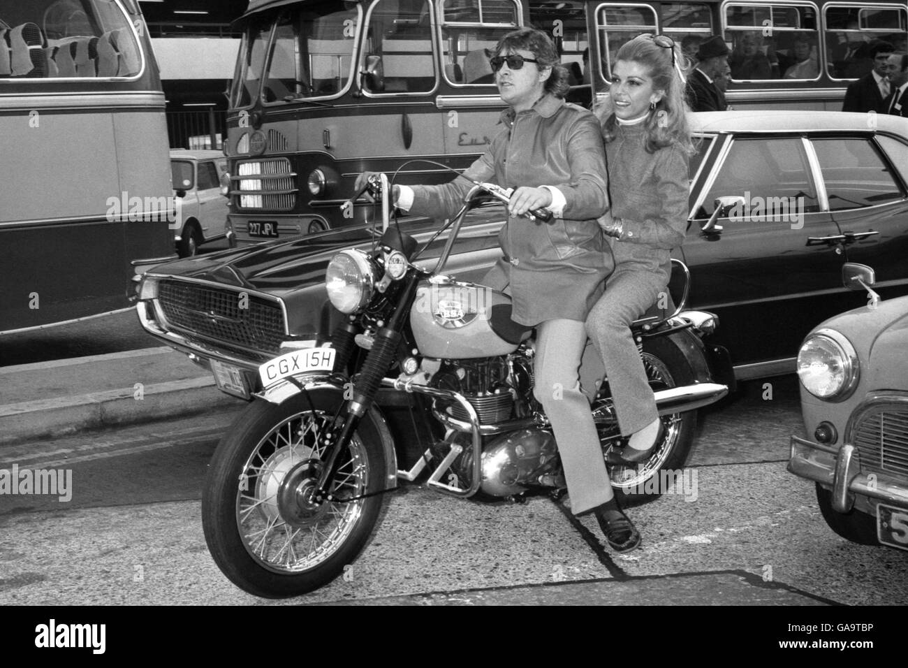 Nancy Sinatra ready to break into a song of the road as she prepares to roar along on the back of a motor bike with record producer Mickey Most in the front seat. Stock Photo