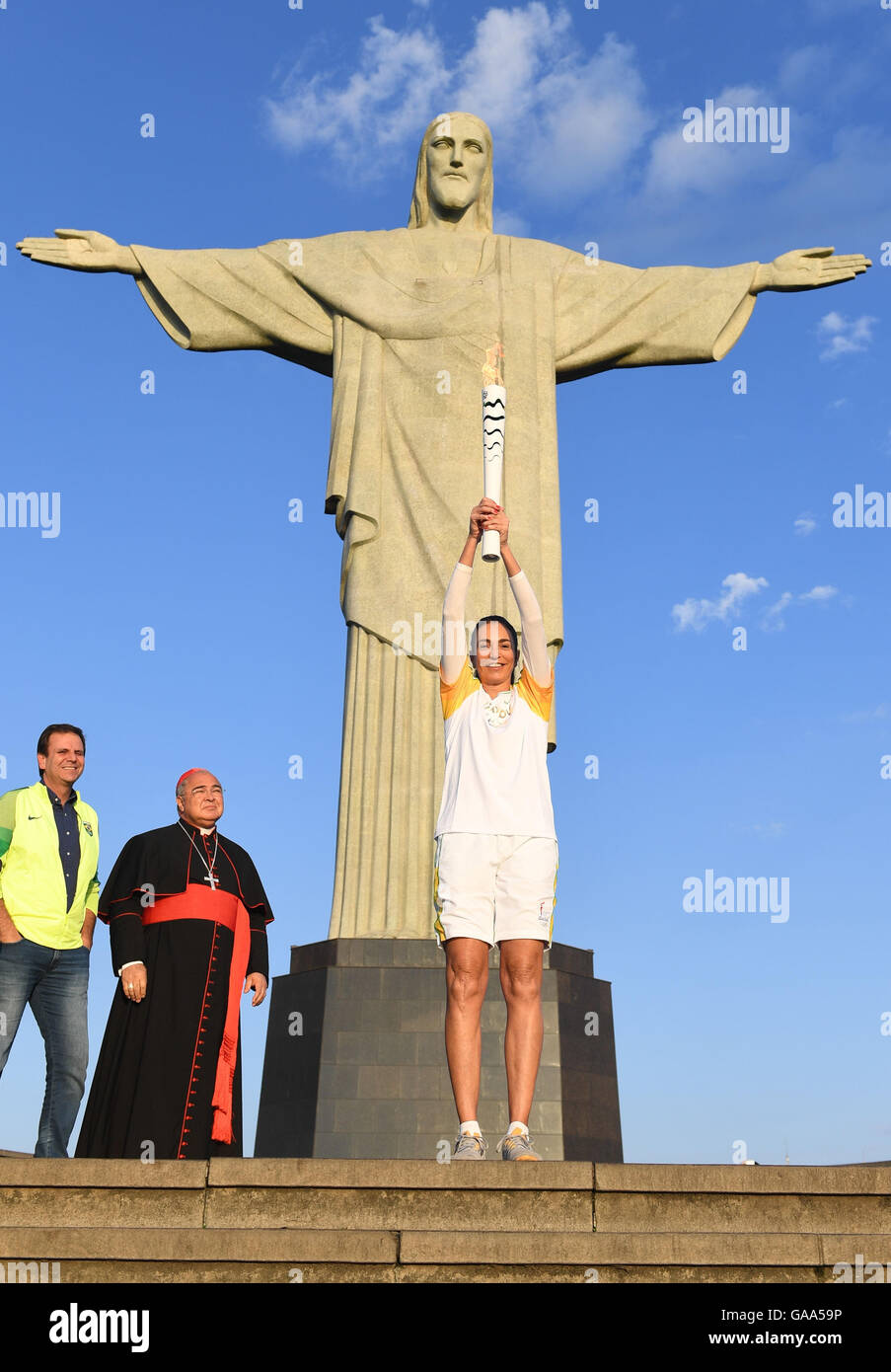 Rio de Janeiro, Brazil. 5th Aug, 2016. Brazilian former volleyball player Maria Isabel Barroso holds the Olympic torch next to Eduardo Paes (L), Mayor of Rio de Janeiro, and Archbishop of Rio de Janeiro, Orani Joao Tempesta (2-L), during the Olympic Torch Relay in front of Christ the Redeemer statue early in the morning prior to the Rio 2016 Olympic Games in Rio de Janeiro, Brazil, 5 August 2016. Rio 2016 Olympic Games take place from 05 to 21 August. Photo: Sebastian Kahnert/dpa/Alamy Live News Stock Photo