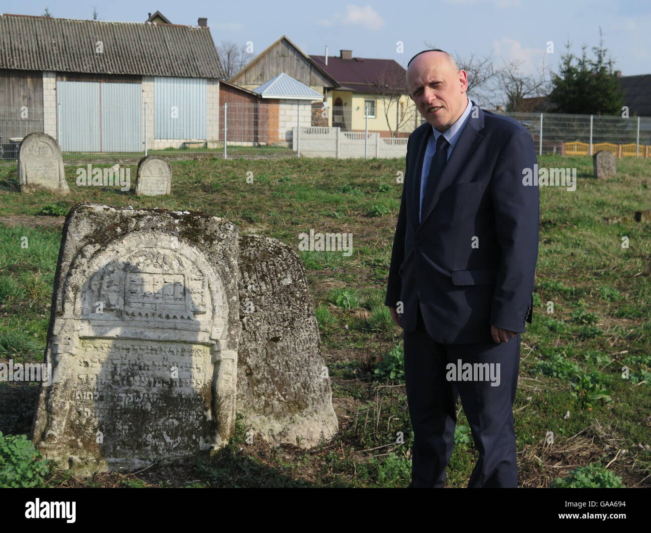 Frampol, Poland. 6th Apr, 2016. Phil Carmel of the European Jewish Cemeteries Initiative standing next to one of the few gravestones left on the Jewish cemetery in Frampol, Poland, 6 April 2016. A European initiative and group of volunteers supports the preservation of graves that are not visited anymore. PHOTO: EVA-MARIA-KRAFCZYK/dpa/Alamy Live News Stock Photo