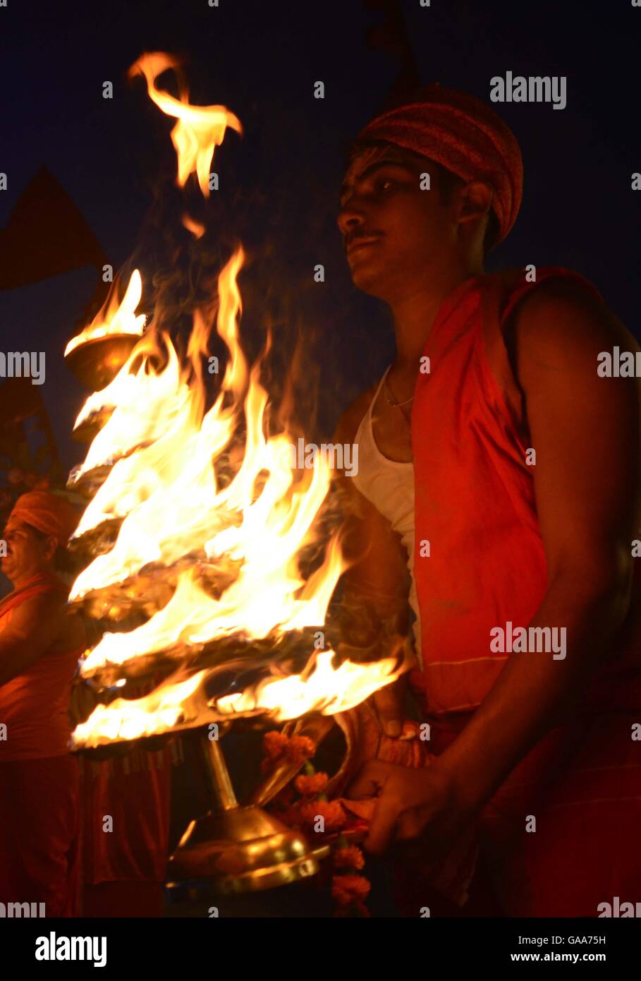 Allahabad, Uttar Pradesh, India. 5th Aug, 2016. Allahabad: Priest rotate traditional oil lamp as they performing evening prayer on the occasion of Hariyali Teej at Sangan, the confluence of River Ganga, Yamuna and Mythological Saraswati in Allahabad, Hariyali teej is a generic name for a number of festivals that are celebrated in Nepal, Northern and Western India. Haryali Teej, Kajari Teej and Hartalika Teej welcome the monsoon season and are celebrated primarily by girls and women, with songs, dancing and prayer rituals. The monsoon festivals of Teej are primarily dedicated to Goddess Parv Stock Photo