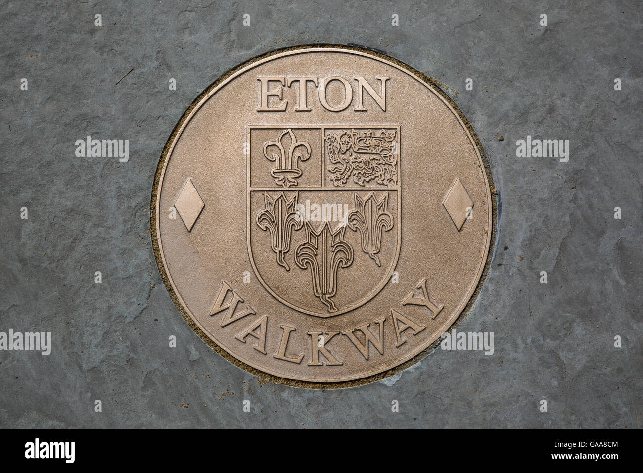 Eton, UK. 5th August, 2016. A bronze roundel marker for the Eton Walkway. It features the Eton town crest, comprising three lilies, a lion and a fleur-de-lys and granted by Henry VI in 1449. The two-mile walkway connects 18 significant points of interest around the historic town. Credit:  Mark Kerrison/Alamy Live News Stock Photo